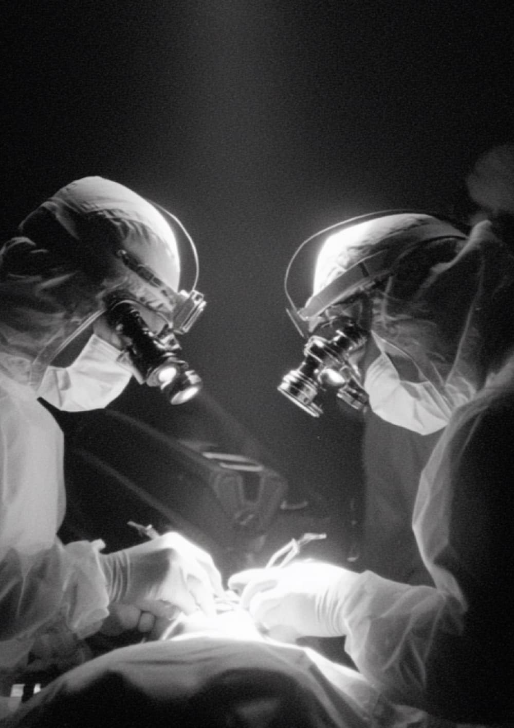 Two dentists at work under a single light